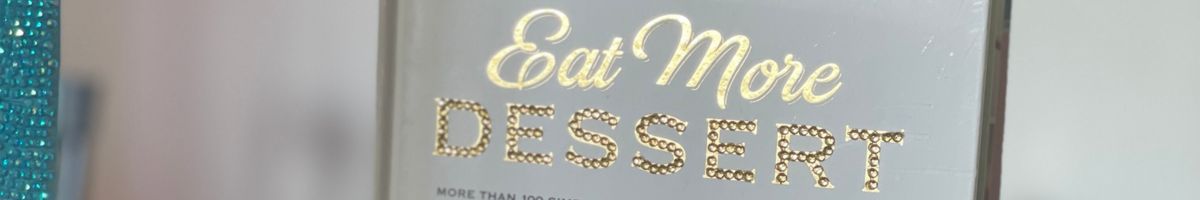 Book titled "Eat More Dessert" decorated with gold rhinestones during a Cozy Girls Getaways book bedazzling activity