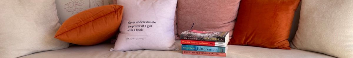 Book lover home decor scene with stacked books and empowering pillow quote for Cozy Girls Getaways