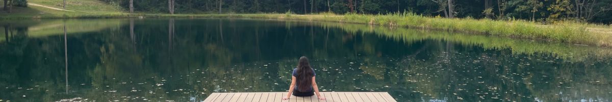 Guest enjoying quiet reflection on a wooden dock by the lake at a boutique book retreat